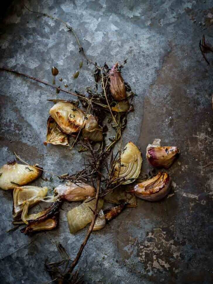 Het perfecte lamsbout recept met rozemarijn en knoflook. Uit de oven. Plaat met gebakken knoflook en ui