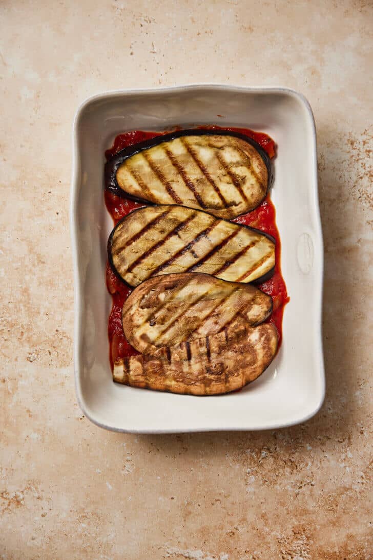 Toevoegen van de plakken aubergine aan de ovenschaal