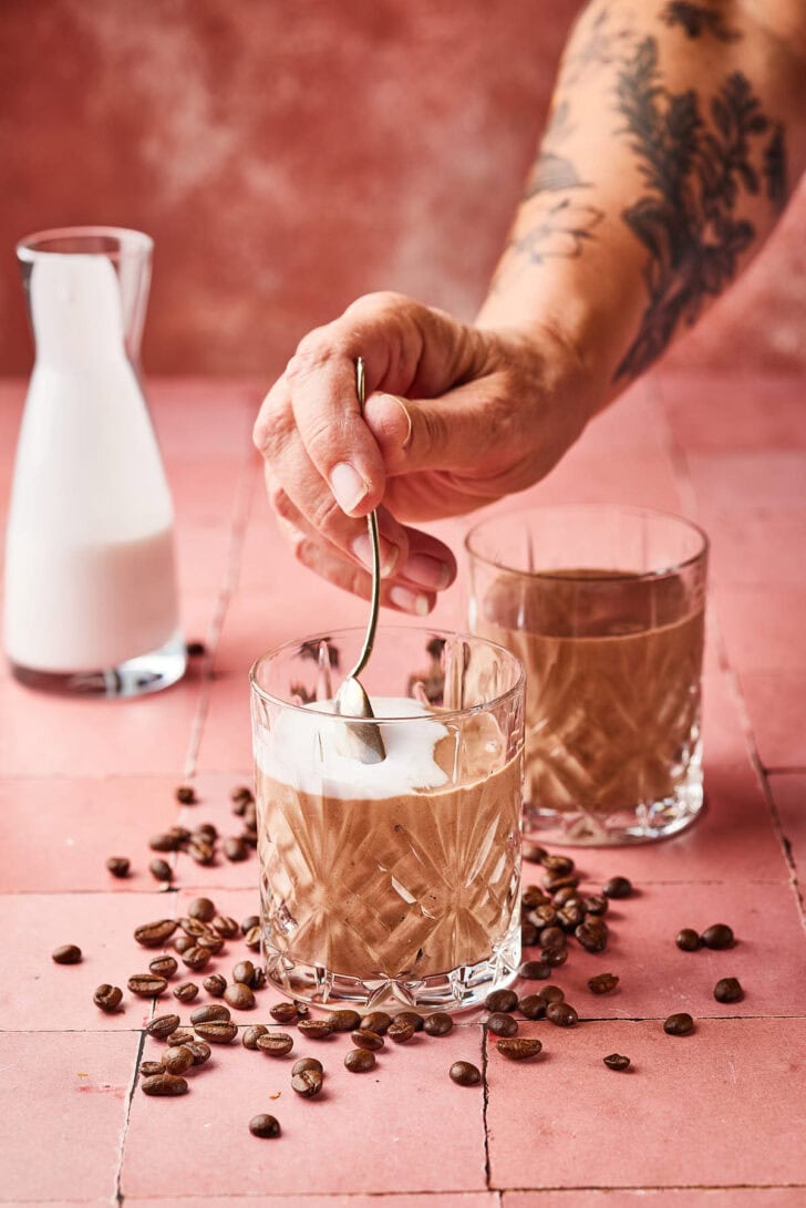 Lactosevrije ijskoffie. Hand roert cashewmelk erdoor