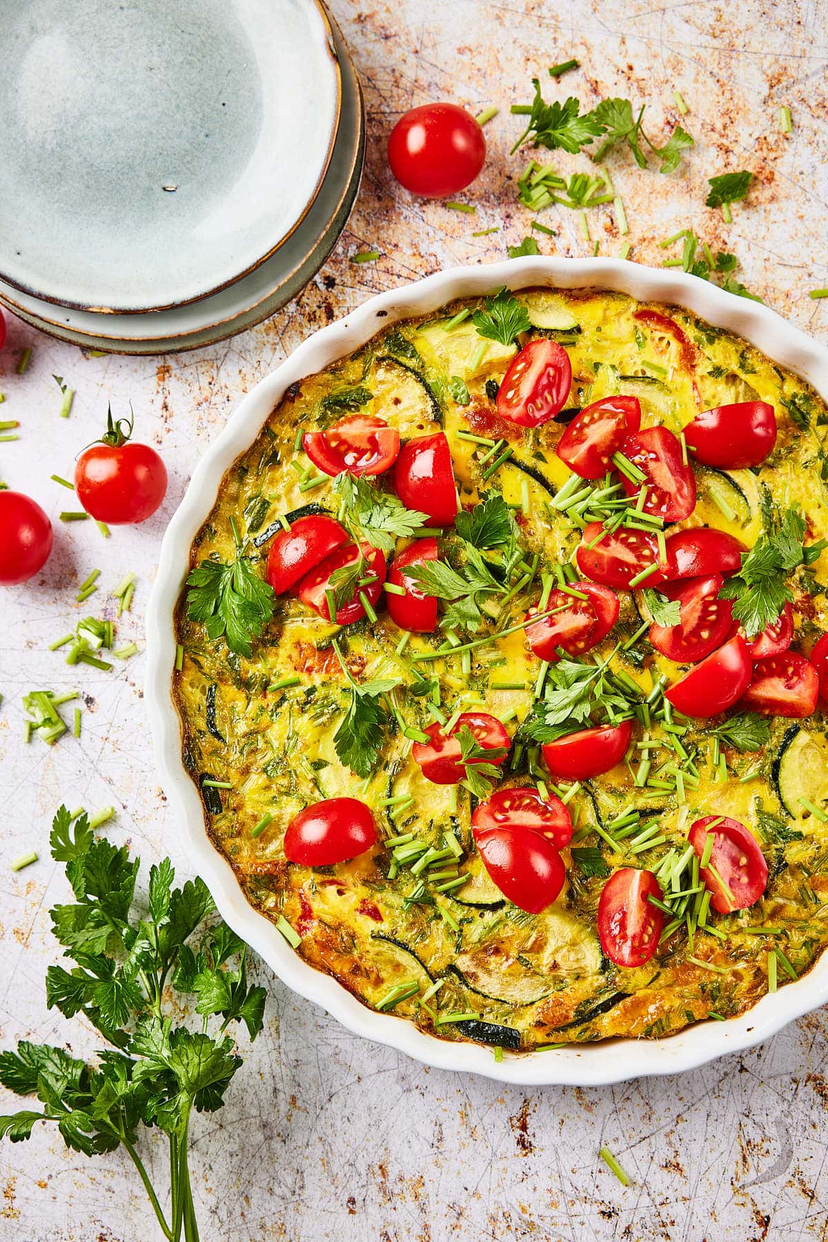 De ongesneden courgette quiche met bordjes in de achtergrond