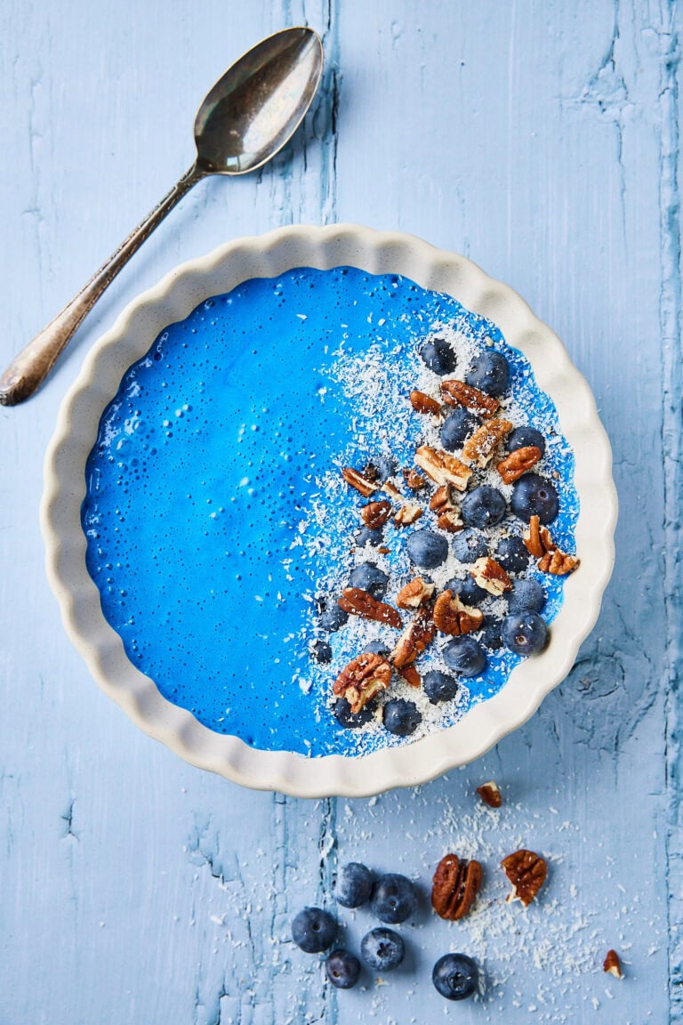 Blauwe spirulina smoothiebowl met blauwe bessen en noten.
